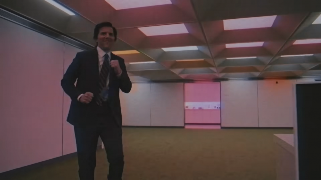 A worker dances in a generally unatmospheric office room, from the TV series Severance. Credit: Apple TV.