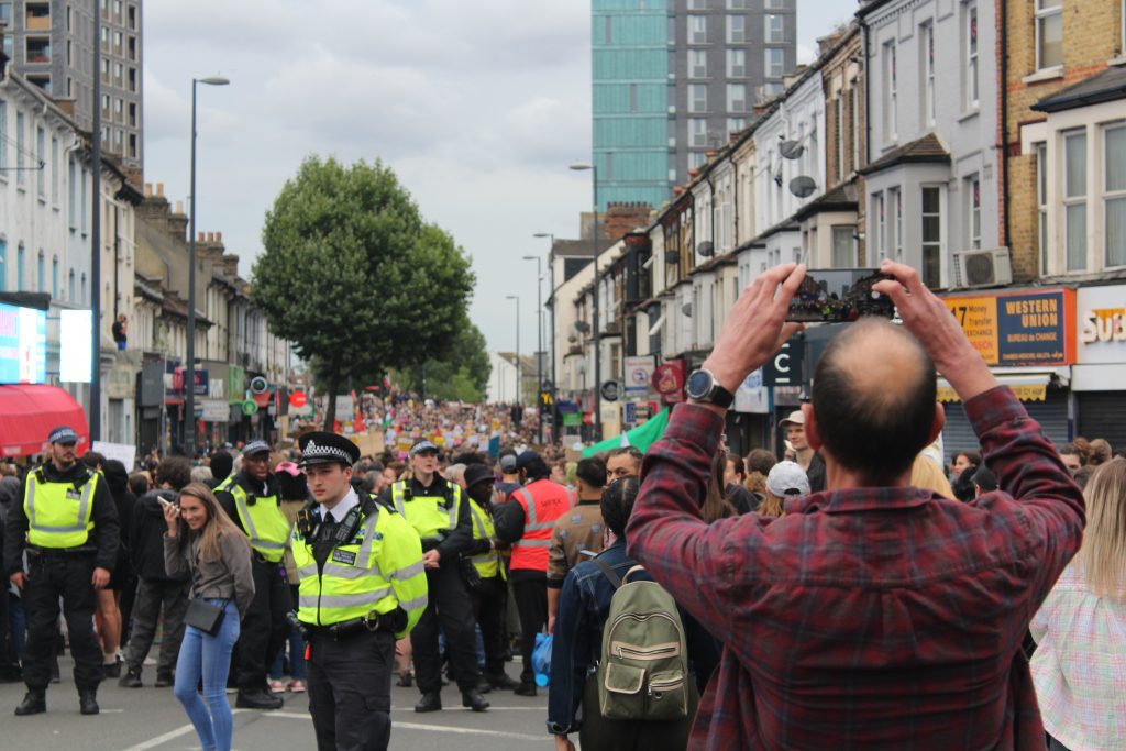A man photographs a heavily-policed protest in Walthamstow, London.