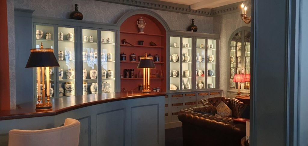An apothecary's store, with many china jars of herbs lining walls of cases.
