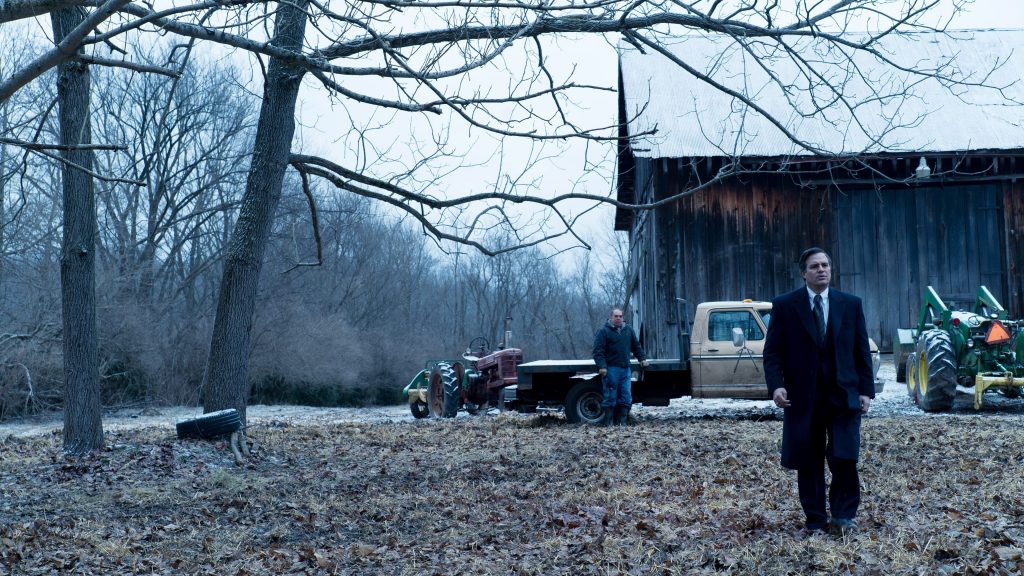 Mark Rufallo walks through a farm yard in winter, as the morose farmer watches him.