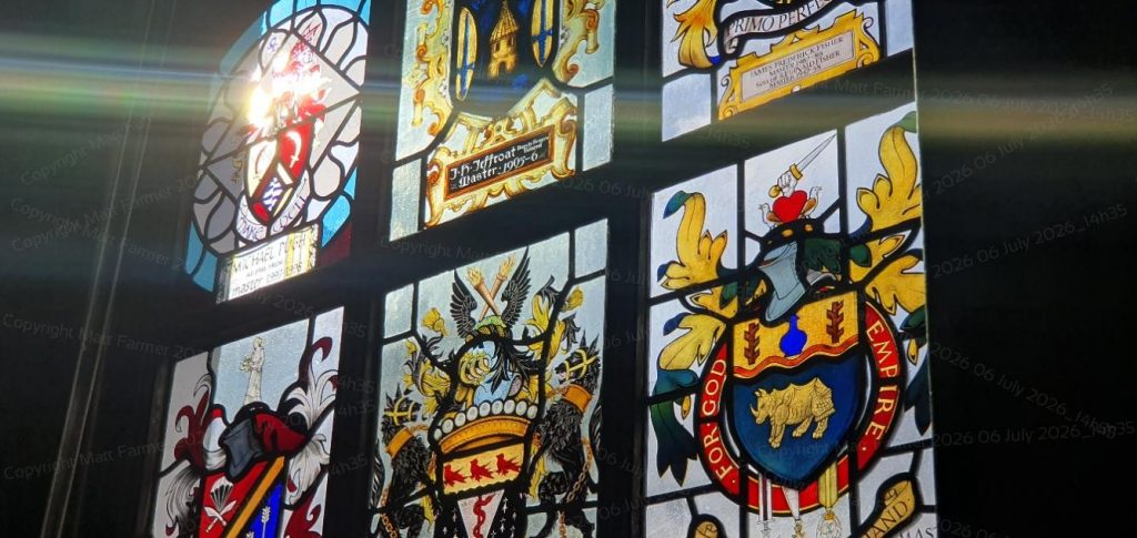 Light shines through a stained glass window, decorated with heraldry